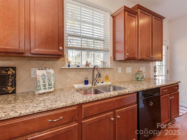 kitchen with a sink, light stone countertops, decorative backsplash, and dishwasher