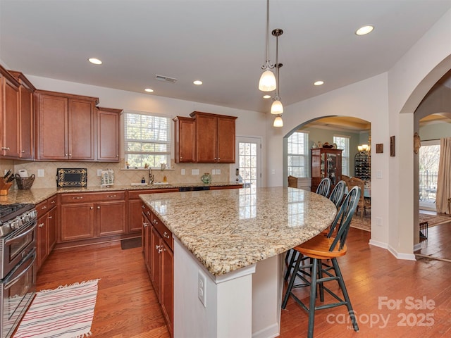 kitchen with arched walkways, a sink, a center island, and double oven range