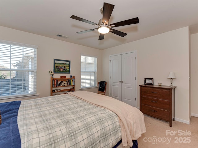 bedroom with light colored carpet, a closet, visible vents, and multiple windows