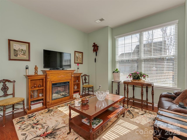 living room with baseboards, a fireplace, visible vents, and wood finished floors