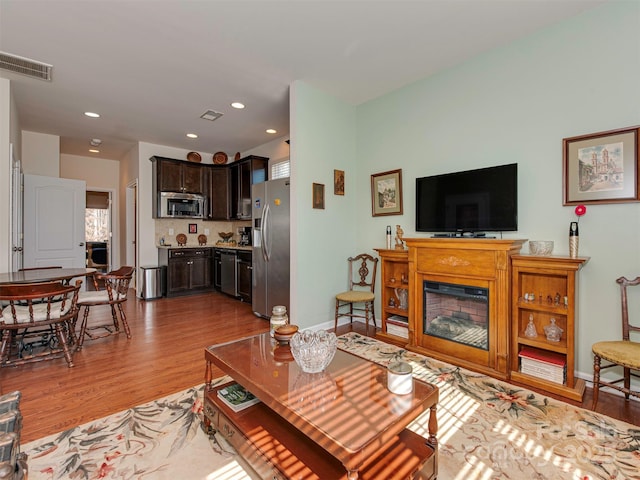 living room with light wood finished floors, baseboards, visible vents, a fireplace, and recessed lighting