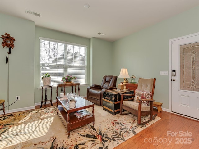 living area with wood finished floors, visible vents, and baseboards