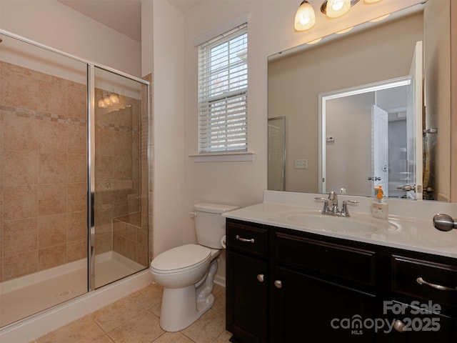 bathroom featuring tile patterned flooring, toilet, a shower stall, and vanity