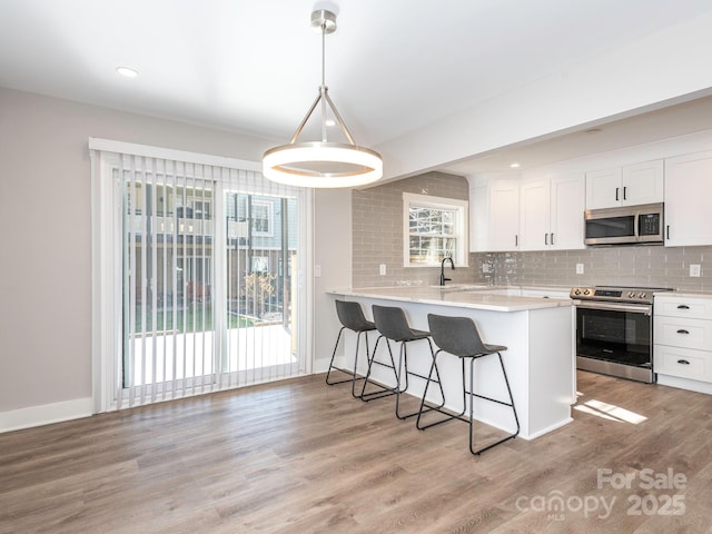 kitchen featuring light wood finished floors, appliances with stainless steel finishes, a breakfast bar, and decorative backsplash