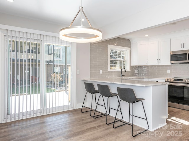 kitchen featuring stainless steel appliances, light wood-type flooring, backsplash, and a kitchen breakfast bar