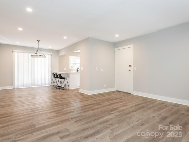 spare room featuring light wood-style flooring, baseboards, a sink, and recessed lighting