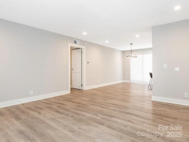 empty room with light wood-style floors, recessed lighting, visible vents, and baseboards