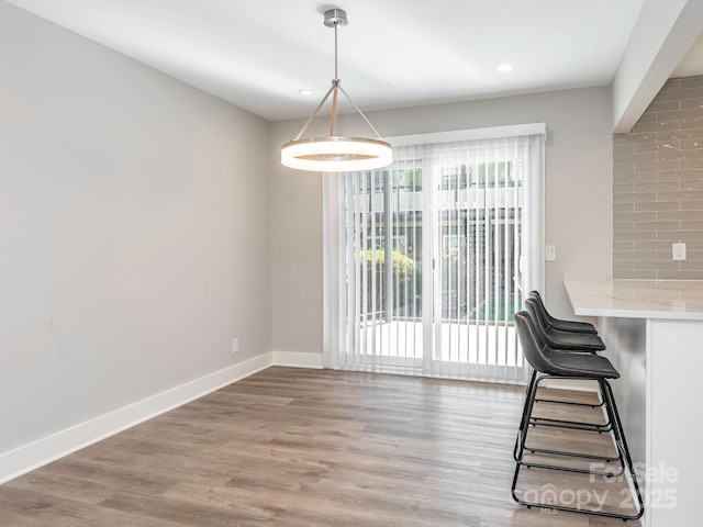 unfurnished dining area featuring a wealth of natural light, recessed lighting, baseboards, and wood finished floors