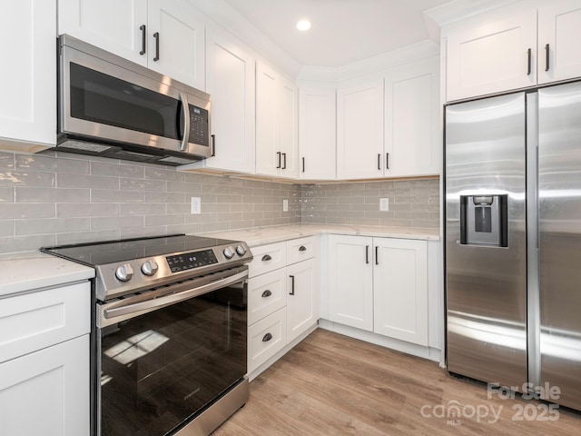 kitchen featuring light stone counters, stainless steel appliances, white cabinetry, backsplash, and light wood finished floors