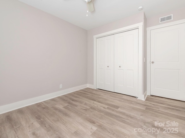 unfurnished bedroom featuring light wood-style floors, a closet, visible vents, and baseboards