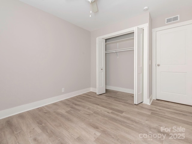 unfurnished bedroom with a closet, baseboards, visible vents, and light wood finished floors