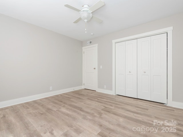 unfurnished bedroom featuring ceiling fan, visible vents, baseboards, a closet, and light wood finished floors