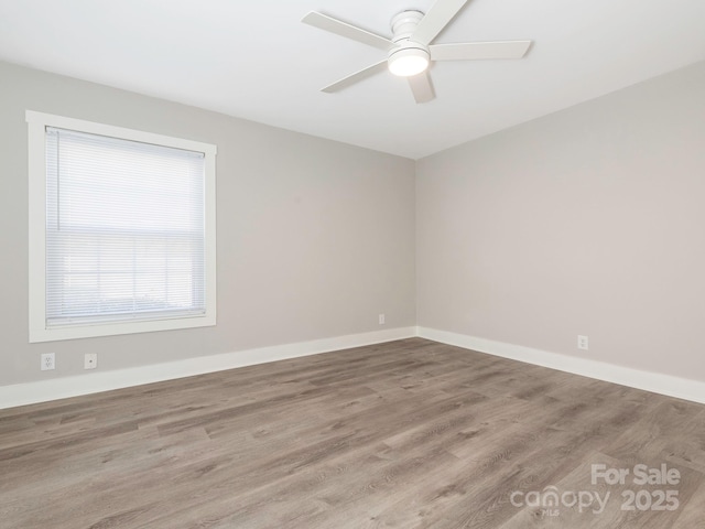 spare room featuring wood finished floors, a ceiling fan, and baseboards