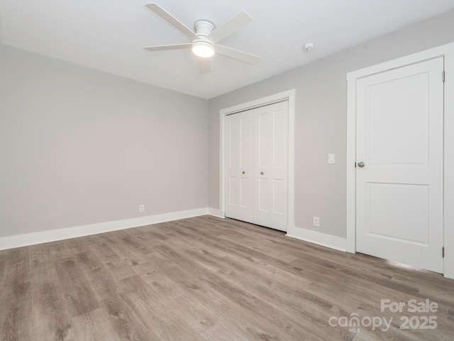 unfurnished bedroom featuring light wood finished floors, a closet, a ceiling fan, and baseboards