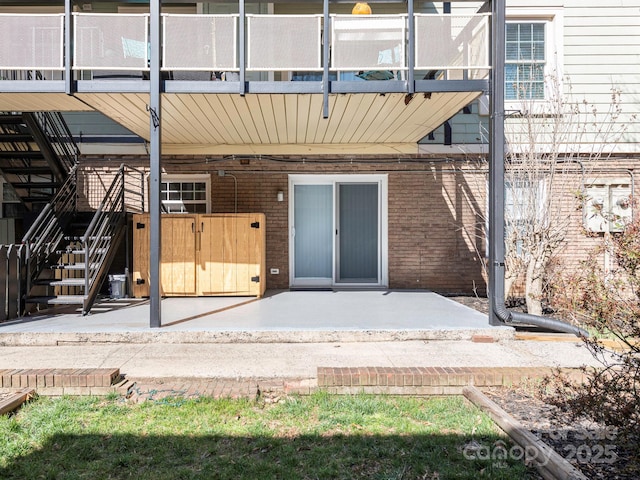 exterior space featuring brick siding, a patio, and stairway