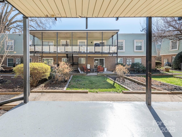 exterior space with stairs, a patio, brick siding, and a front lawn