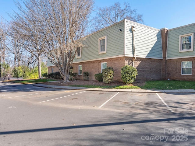 view of home's exterior featuring uncovered parking and brick siding