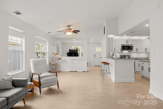 kitchen featuring light wood finished floors, a breakfast bar area, visible vents, appliances with stainless steel finishes, and open floor plan