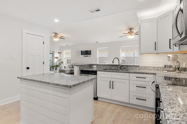 kitchen featuring a peninsula, electric range, a sink, visible vents, and dishwasher