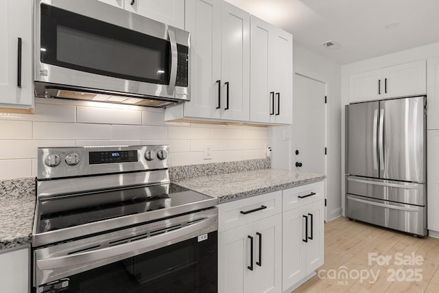 kitchen with white cabinetry, light wood-style flooring, visible vents, and stainless steel appliances