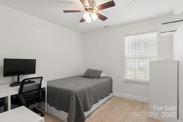 bedroom with ceiling fan, visible vents, light wood-style flooring, and baseboards