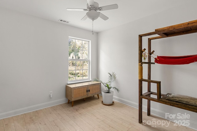 empty room with a ceiling fan, baseboards, visible vents, and light wood finished floors