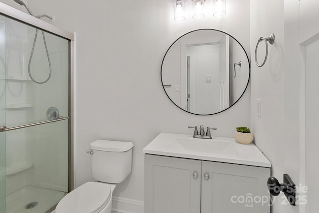 bathroom with a stall shower, baseboards, vanity, and toilet