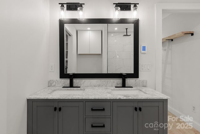 bathroom with double vanity, baseboards, and a sink