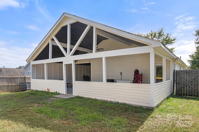 exterior space featuring ceiling fan, a lawn, fence, and a sunroom