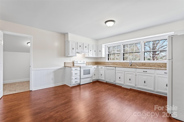 kitchen featuring dark wood finished floors, white cabinetry, a sink, white appliances, and under cabinet range hood