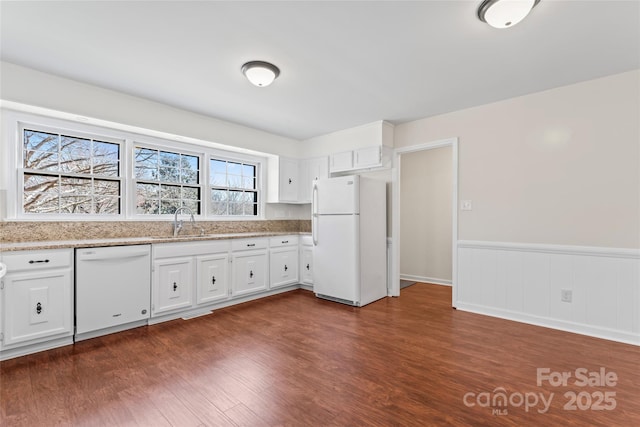 kitchen with dark wood finished floors, white appliances, a wainscoted wall, and a sink