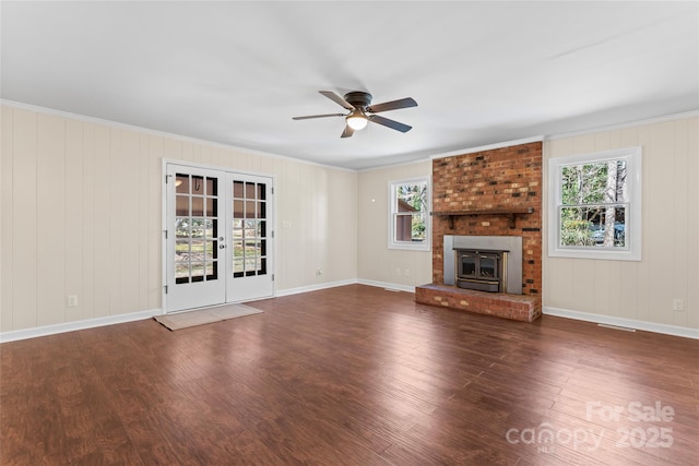 unfurnished living room featuring a wood stove, crown molding, wood finished floors, and french doors