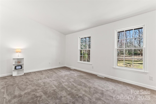 carpeted spare room with baseboards and a healthy amount of sunlight