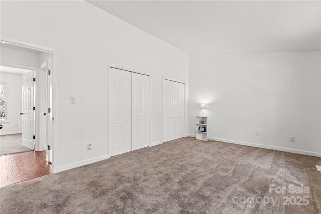 unfurnished bedroom with multiple closets, carpet, and baseboards