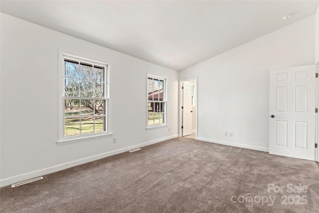 carpeted spare room featuring lofted ceiling, visible vents, and baseboards