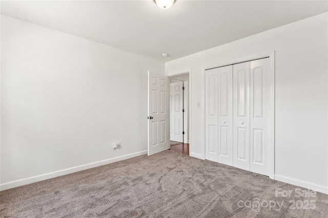 unfurnished bedroom with a closet, carpet flooring, and baseboards