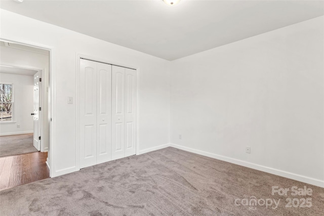 unfurnished bedroom with a closet, carpet, and baseboards