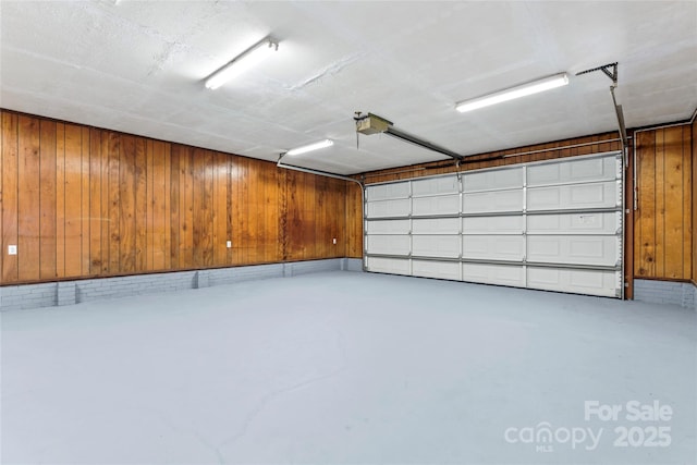 garage featuring wood walls and a garage door opener