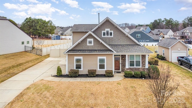 craftsman-style home featuring a front lawn, a shingled roof, fence, and a residential view