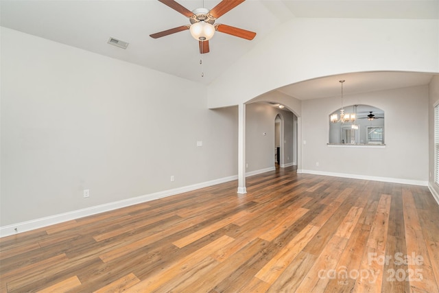 empty room featuring arched walkways, visible vents, hardwood / wood-style floors, baseboards, and ceiling fan with notable chandelier