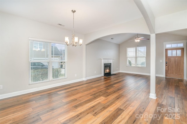 unfurnished living room with visible vents, a fireplace with flush hearth, vaulted ceiling, baseboards, and hardwood / wood-style flooring