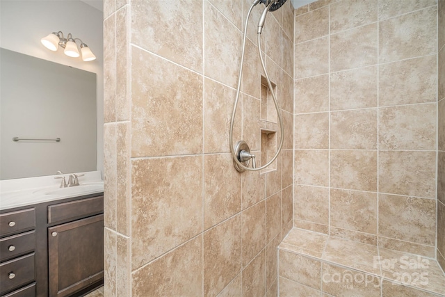 full bathroom with tiled shower and vanity