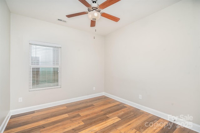 unfurnished room with a ceiling fan, visible vents, baseboards, and wood finished floors