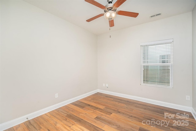 empty room featuring ceiling fan, light wood finished floors, visible vents, and baseboards