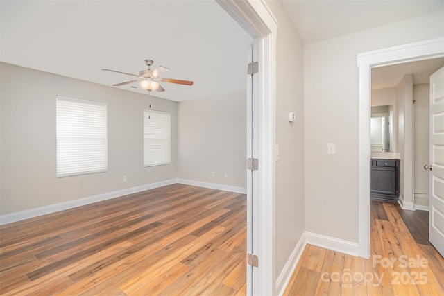 empty room with light wood-type flooring, ceiling fan, and baseboards