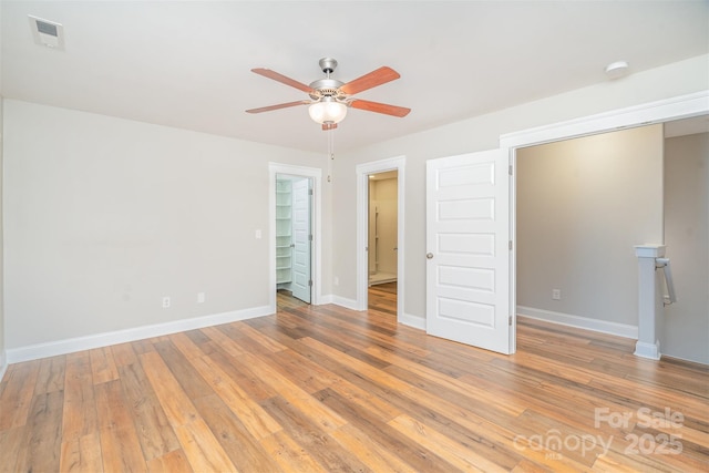 empty room with light wood-style floors, baseboards, visible vents, and a ceiling fan