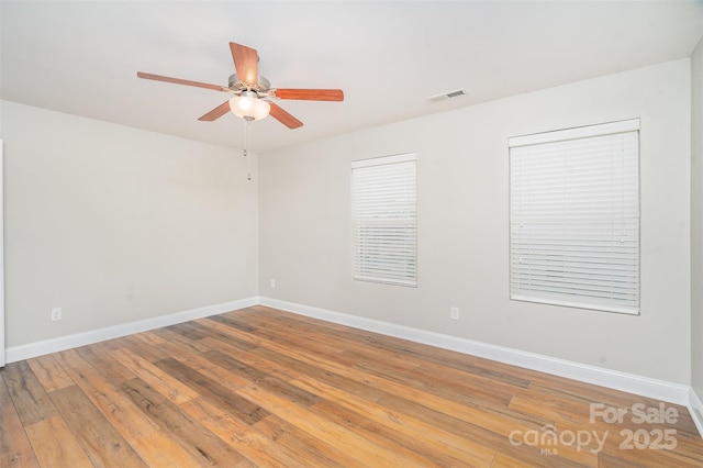 unfurnished room featuring a ceiling fan, baseboards, visible vents, and wood finished floors