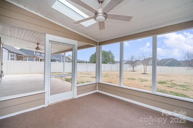 unfurnished sunroom with ceiling fan and vaulted ceiling with skylight