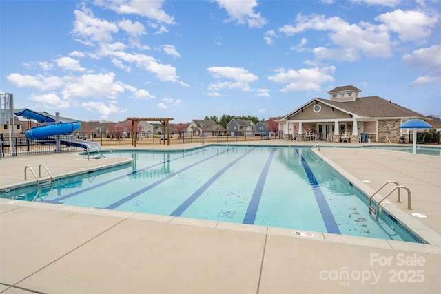 pool with a water slide, a patio area, fence, and a pergola