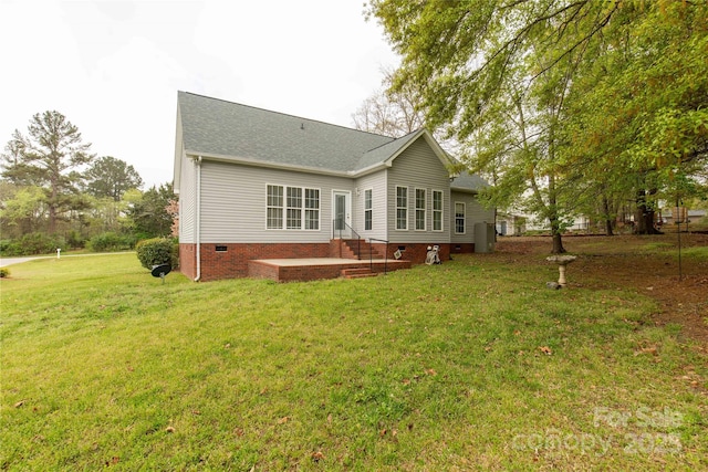 rear view of property featuring a yard, roof with shingles, and crawl space
